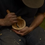 Carving a traditional wooden cup with an axe and knife